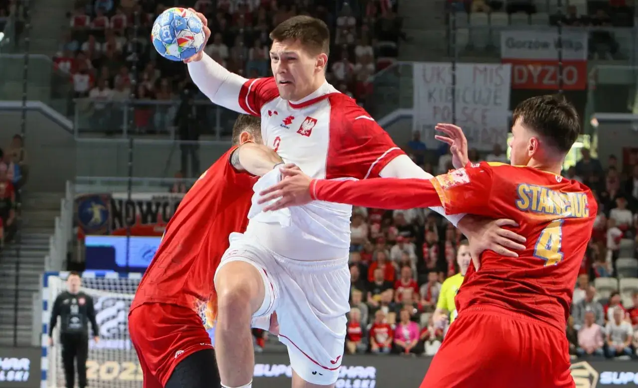 Damian Borkowski w akcji, rzuca piłkę do bramki przeciwnika, otoczony przez obrońc&oacute;w.