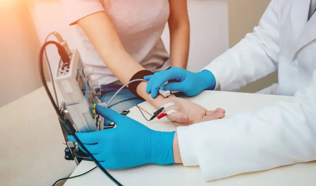 Lekarz wykonuje badanie EMG, sprawdzając przewodnictwo nerwów. To badanie pomaga zdiagnozować problemy z mięśniami i nerwami.