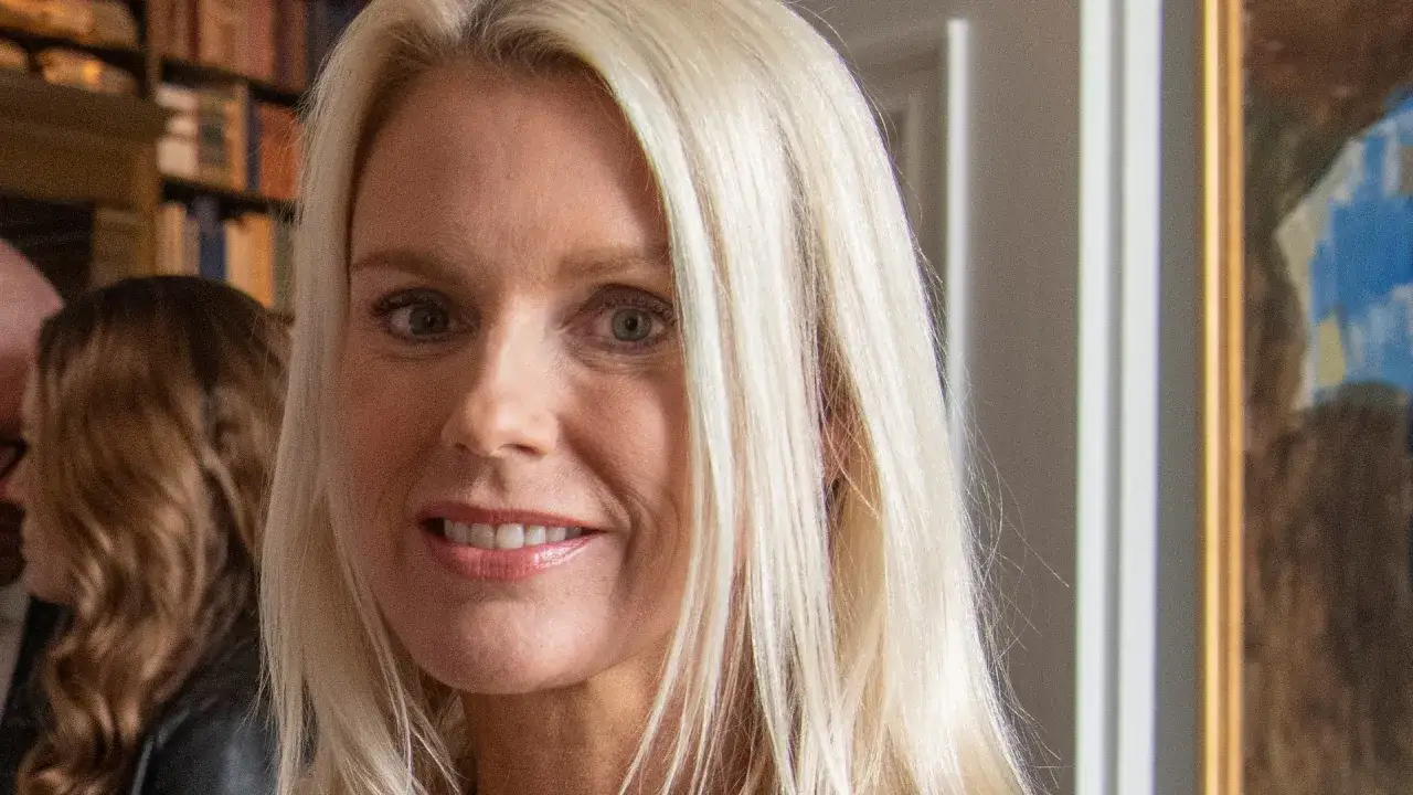 Stina Bergfors ler mot kameran, med sitt blonda h&aring;r fallande &ouml;ver axlarna. I bakgrunden syns bokhyllor och en tavla.