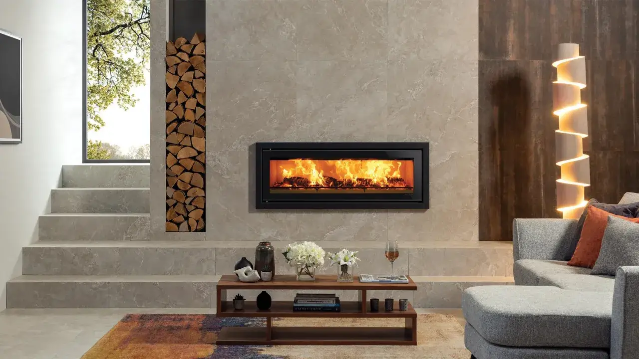 Chimenea moderna con fuego crepitante y una pila de **inserts de le&ntilde;a** junto a una ventana con vistas a la naturaleza.