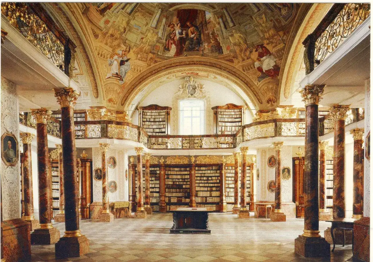 Prunkvolle Bibliothek im Stift Schlierbach mit Deckenmalerei, Säulen und endlosen Bücherregalen.