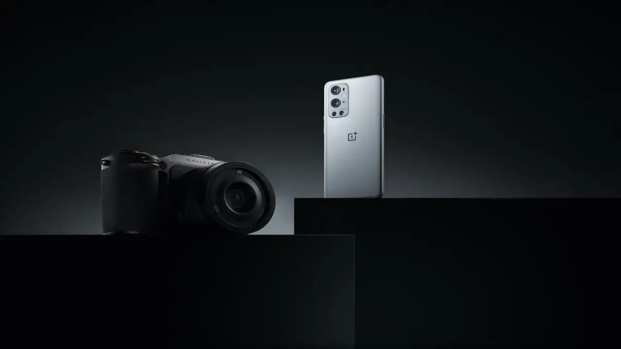En stilren bild som visar en OnePlus-telefon bredvid en Hasselblad-kamera, b&aring;da i en m&ouml;rk och dramatisk milj&ouml;.