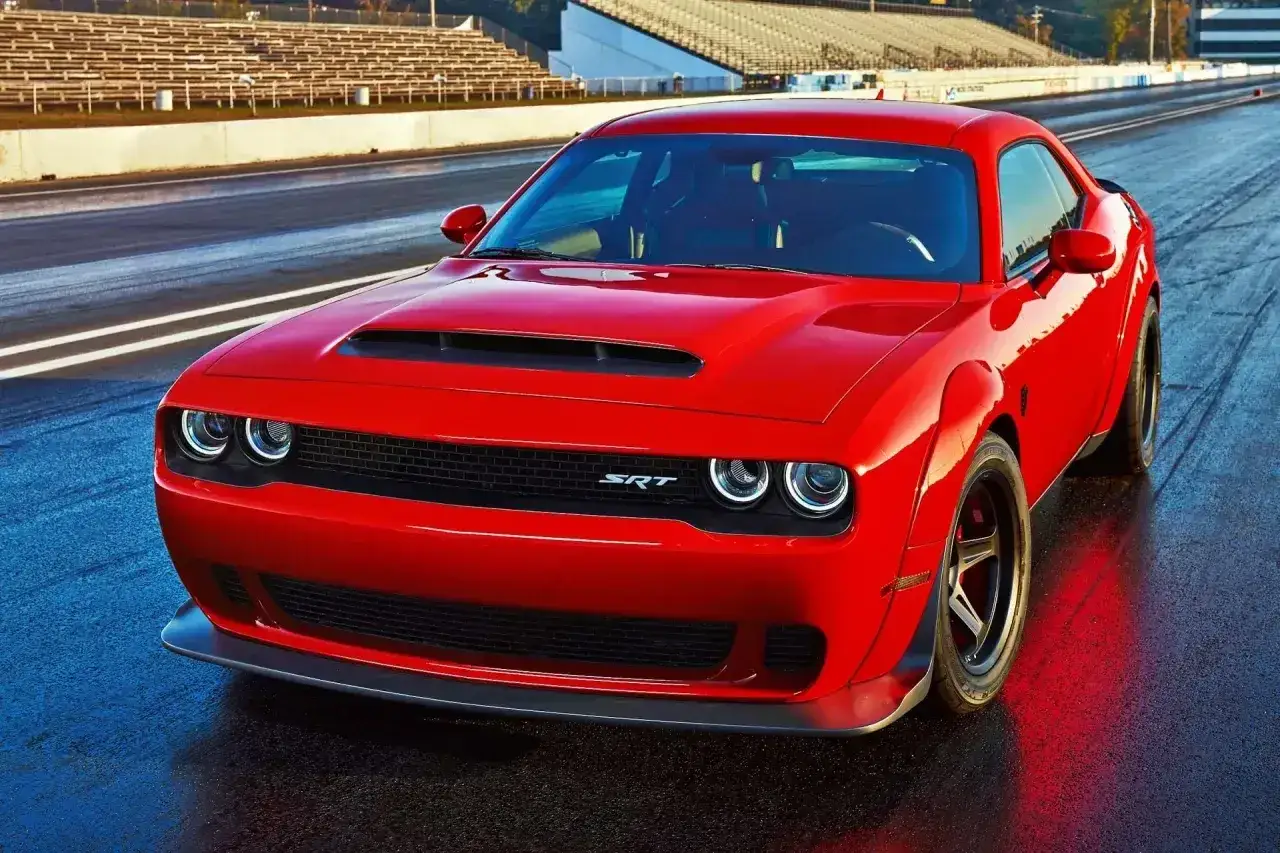 Czerwony Dodge Challenger 5.7 Hemi na torze wyścigowym. Potężny silnik V8, choć jego spalanie jest wysokie, zapewnia niezapomniane wrażenia.