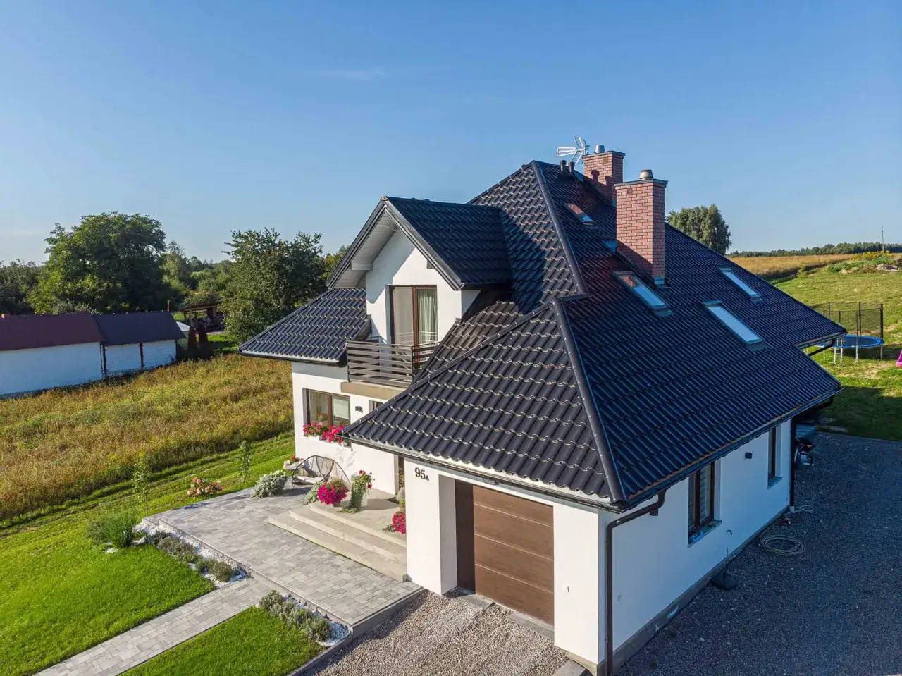 Nowoczesny dom z ciemnym dachem, odpornym na warunki atmosferyczne, idealny dla środowiska o **klasie korozyjności C5**.