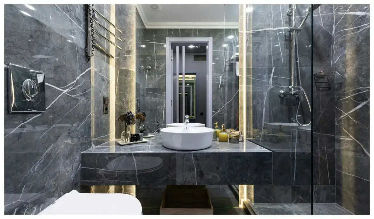 Une **salle de bain de r&ecirc;ve** aux murs de marbre gris, avec vasque ronde, douche moderne et &eacute;clairage d'ambiance.