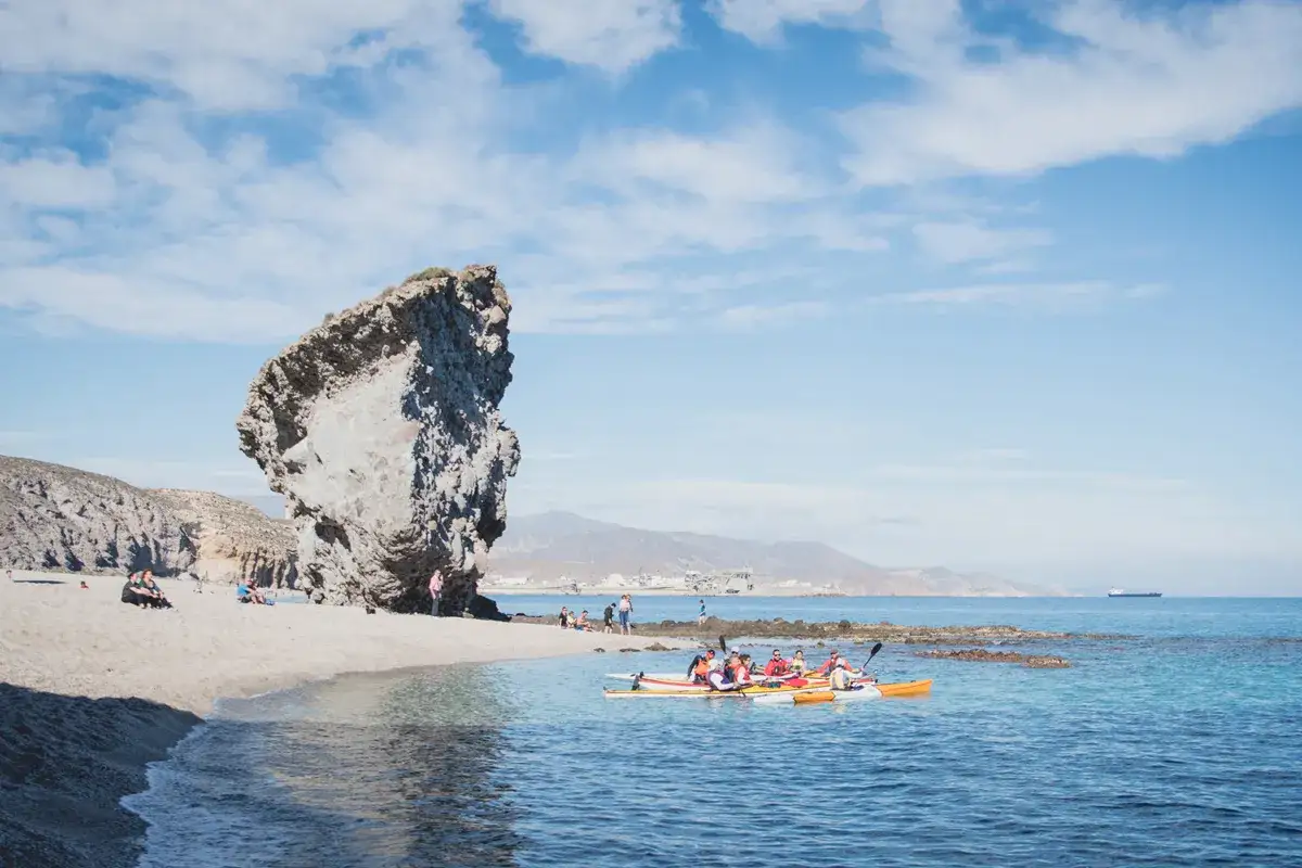 Un grupo de kayakistas disfruta de las aguas cristalinas cerca de una imponente roca en la nijar playa.