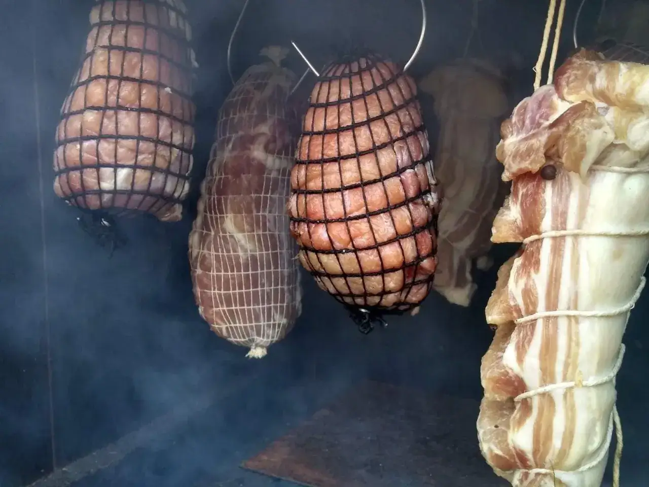 Mięsa w siatkach i boczki wiszą w dymie. Czy brzoza nadaje się do wędzenia? Dym sugeruje, że tak!