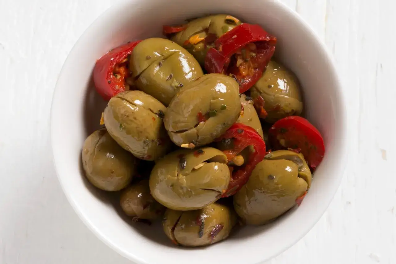 Olive verdi schiacciate con peperoncino rosso, pronte per essere gustate. Un antipasto semplice e saporito, perfetto per chi ama il gusto deciso.