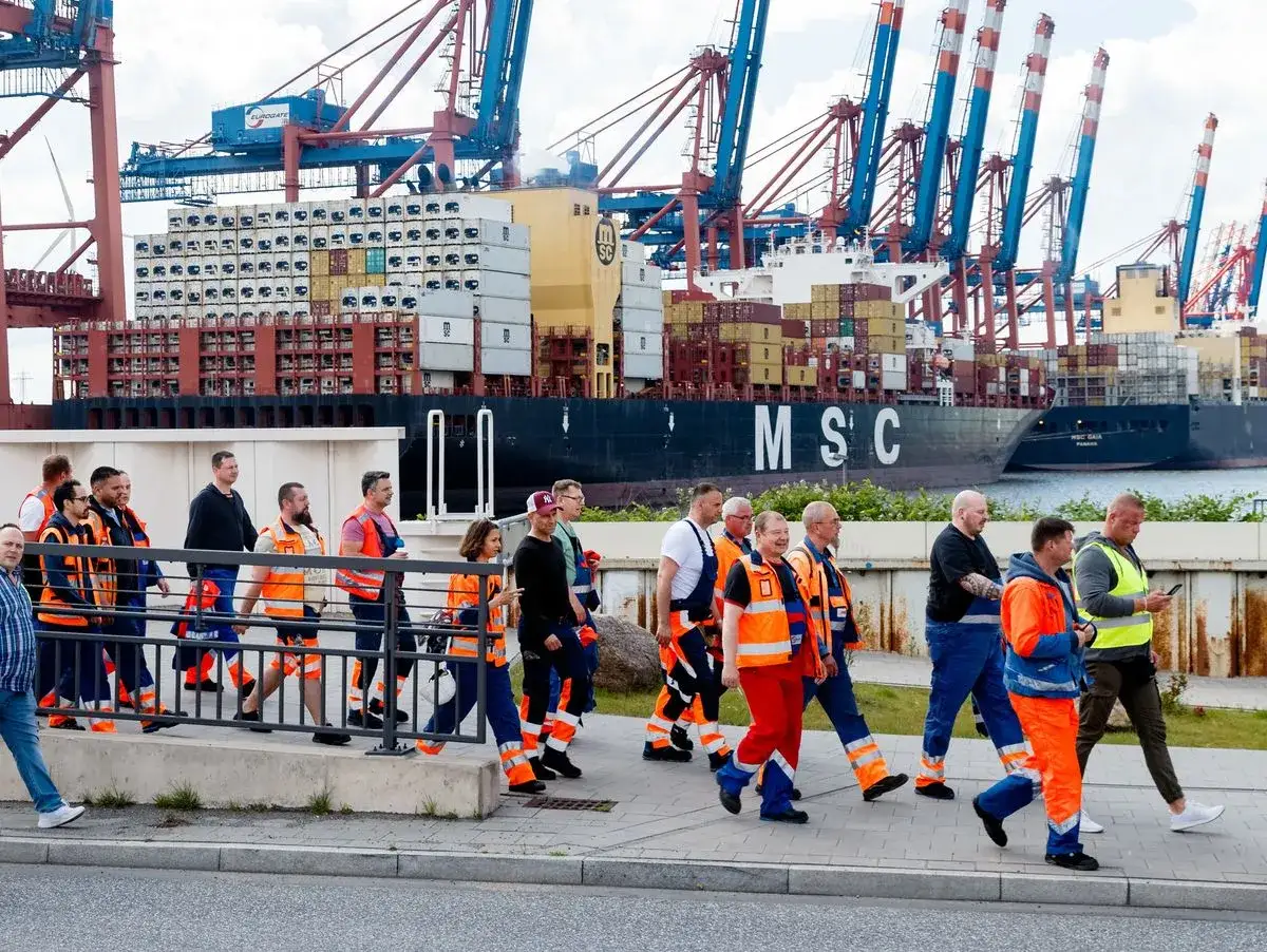 Mitarbeiter einer port agency gehen an einem Containerschiff vorbei.