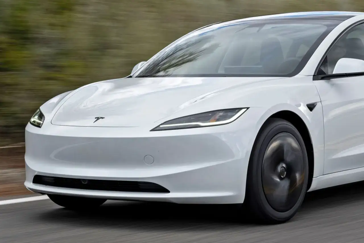 Biały samochód Tesla pędzi po drodze, jego aerodynamiczna linia podkreśla nowoczesny design.