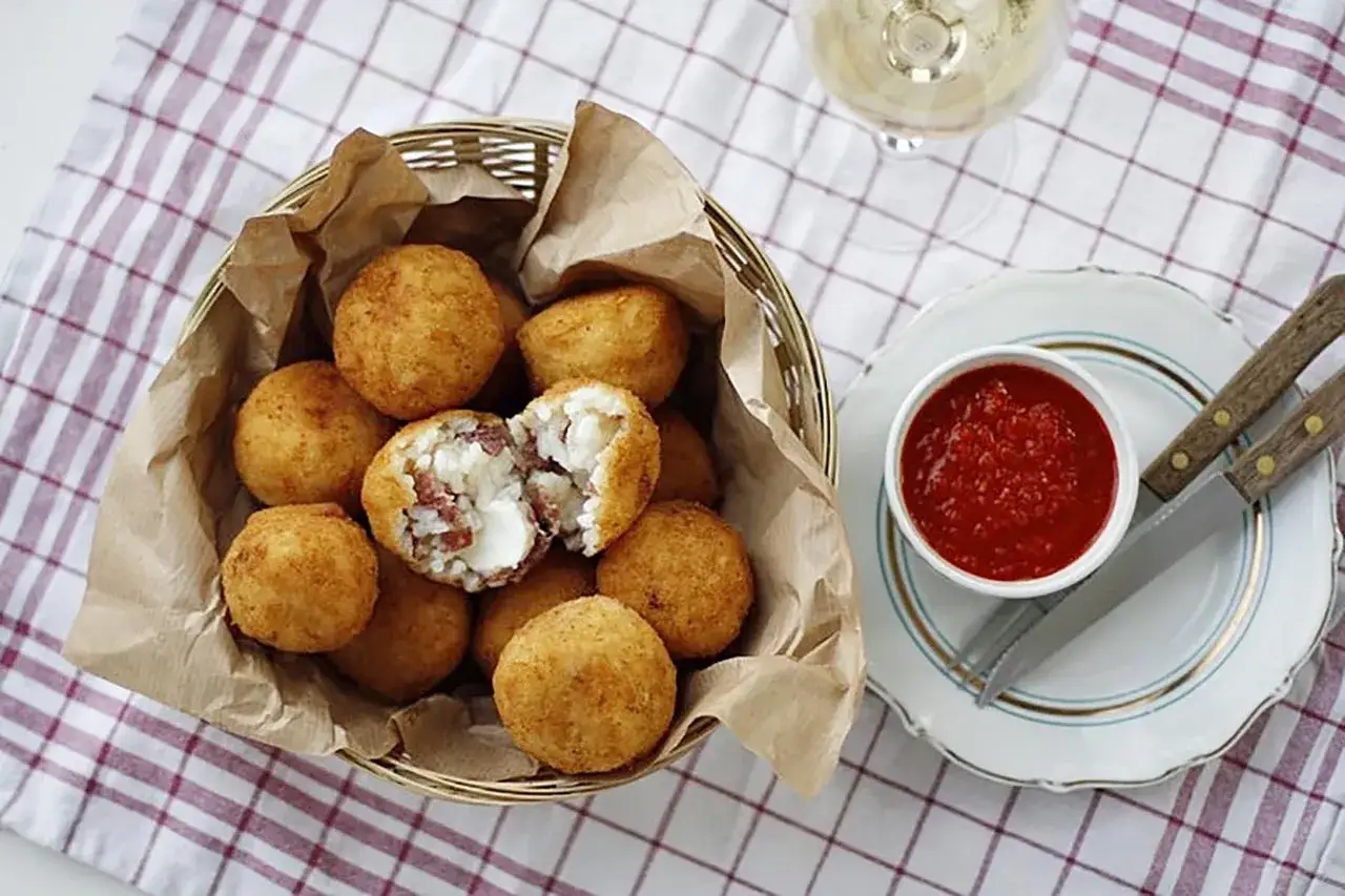 Arancini co to? Złociste kulki ryżowe z nadzieniem, podane z sosem pomidorowym. Pyszna włoska przekąska.