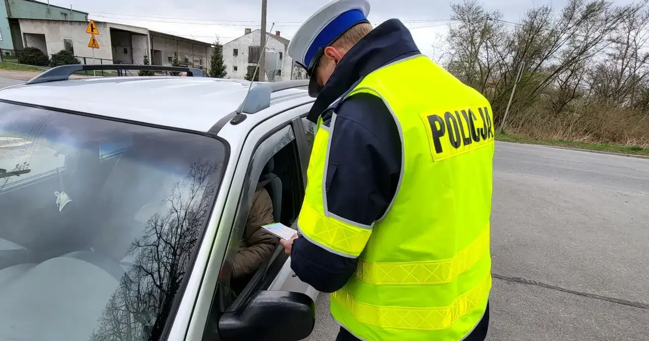 Policjant w kamizelce odblaskowej wręcza kierowcy dokument. Czy to będzie mandat?