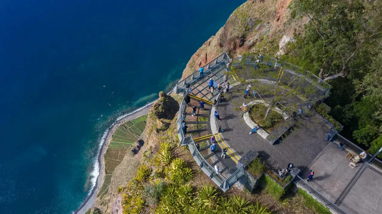 Widok z klifu na Maderze, taras widokowy z ludźmi, ocean i tarasowe pola. Co zobaczyć na Maderze?