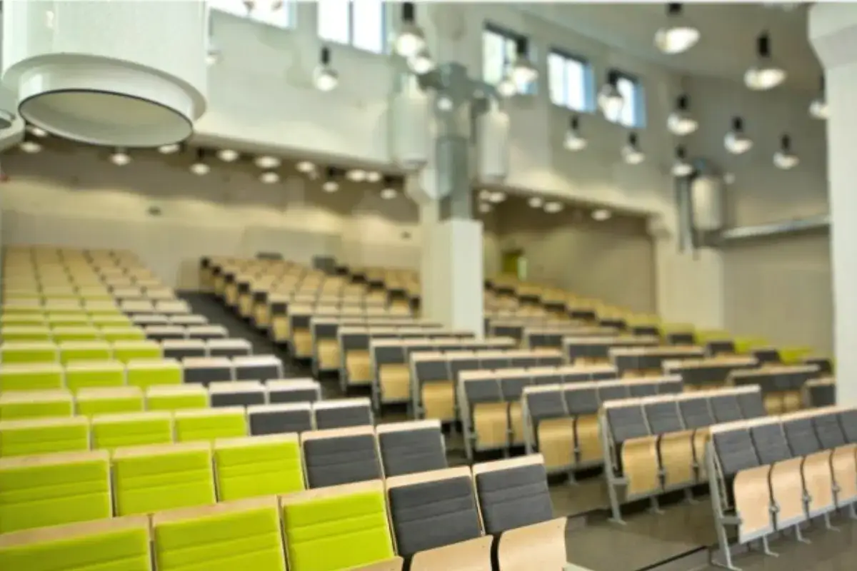 Puste rzędy zielonych i szarych krzeseł w sali wykładowej SWPS Wrocław, gotowe na studentów.