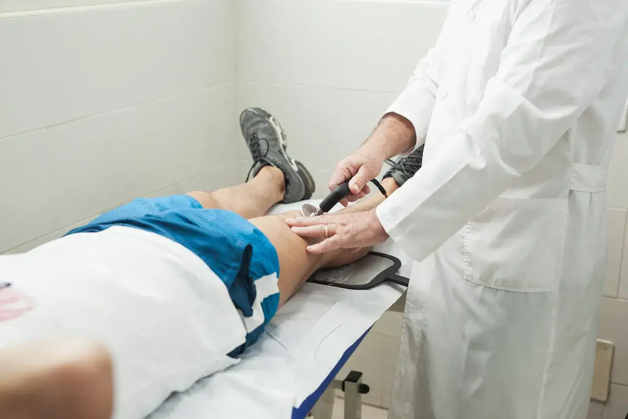 Medico esegue ipertermia terapia su paziente sdraiato, applicando un dispositivo sulla gamba.