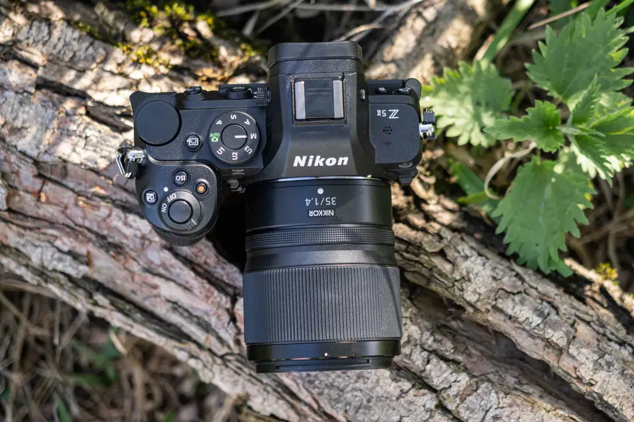 Nikon Z5 II z obiektywem Nikkor 35mm f/1.4 leży na pniu drzewa.