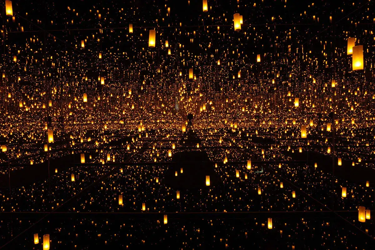 Installation lumineuse infinie, une œuvre de Yayoi Kusama, où des milliers de lanternes dorées créent un univers scintillant et hypnotique.