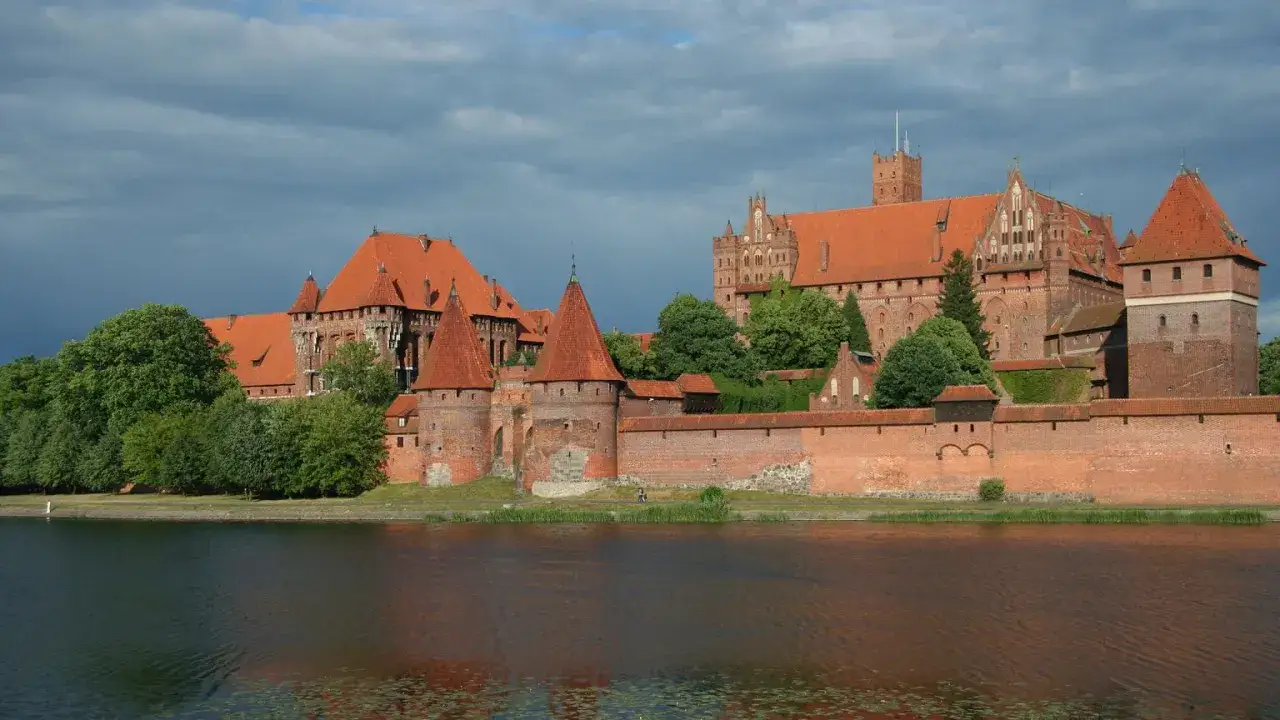 Potężny zamek z czerwonej cegły, największy zamek na świecie, wznosi się nad wodą.