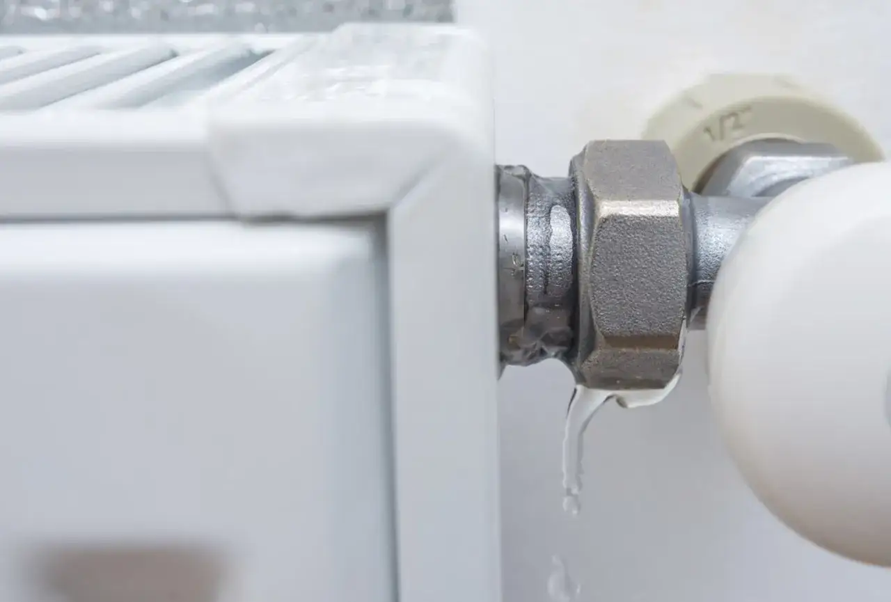 Un radiador que gotea, con gotas de agua cayendo de la conexi&oacute;n de la v&aacute;lvula.