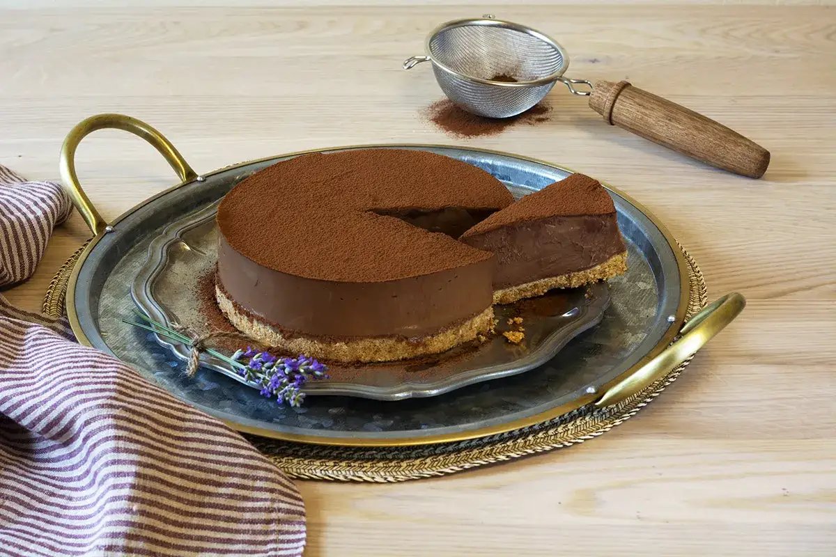 Deliciosa tarta de chocolate, cubierta de cacao en polvo, con una porción servida. Un placer para la vista y el paladar.