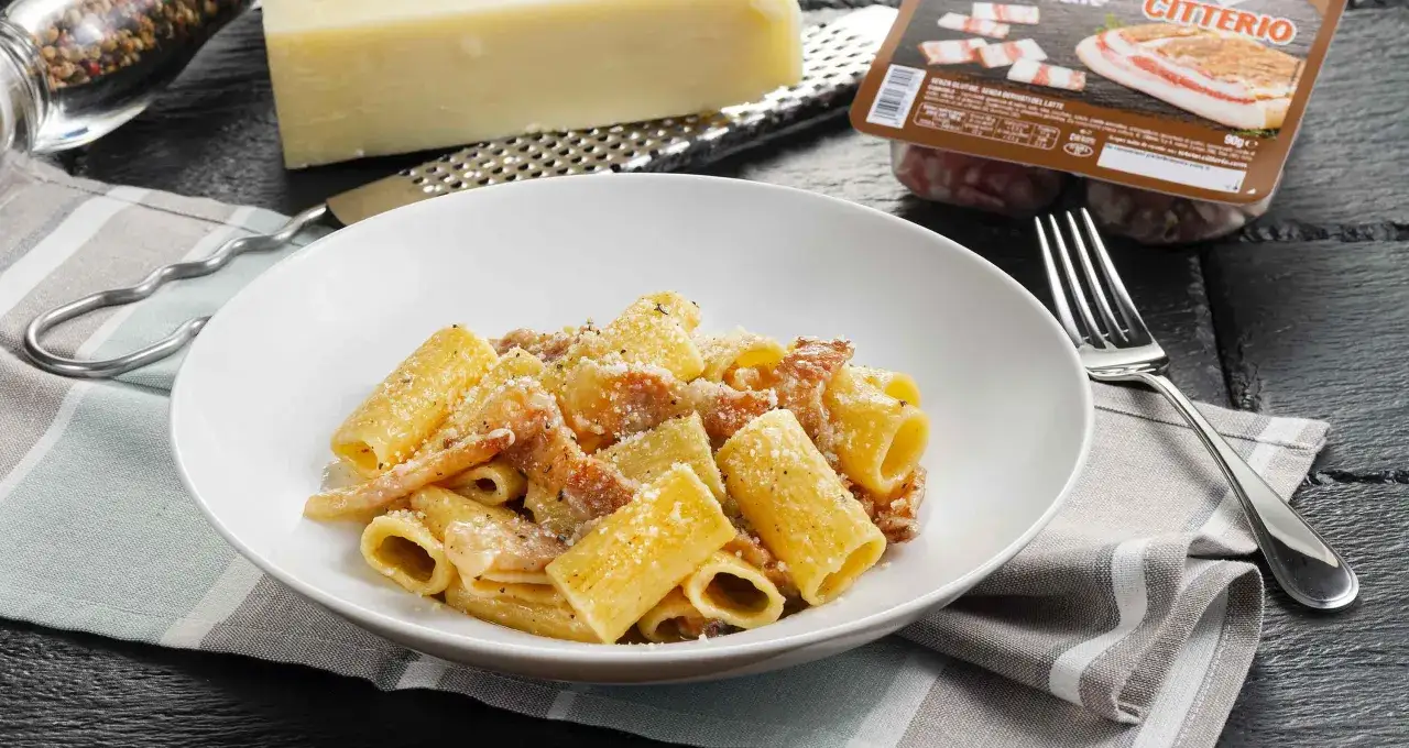Piatto di pasta alla gricia fumante, con guanciale croccante e pecorino romano grattugiato. Ingredienti freschi pronti per un sapore autentico.
