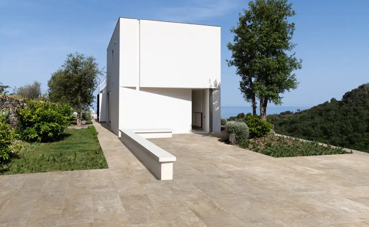 Un moderno giardino pavimentato con un'architettura minimalista e una vista sul mare.