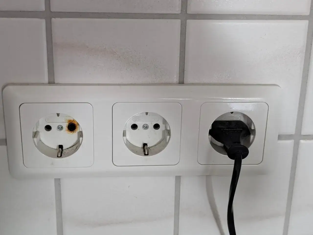 Eine Steckdose ist durchgebrannt, mit deutlichen Brandspuren im linken Anschluss. Ein Stecker ist im rechten Anschluss.