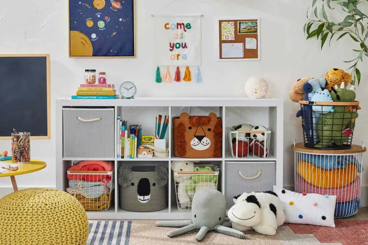 Un cofre de juguete con forma de león guarda tesoros. Alrededor, peluches y cestas organizan la habitación infantil.