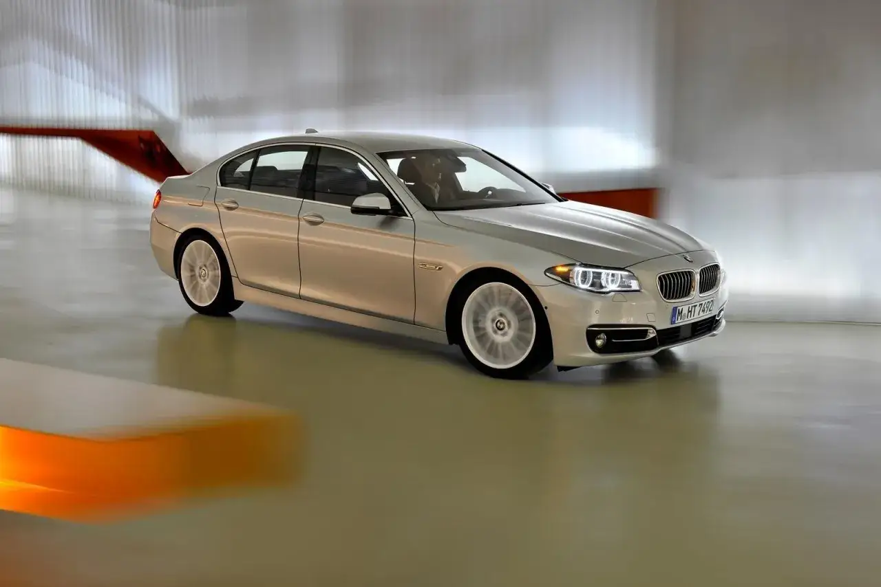 Srebrne bmw f10 lift w ruchu, z rozmytymi kołami, porusza się po nowoczesnym, jasnym wnętrzu.