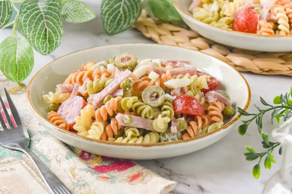 Deliciosa ensalada primavera con pasta tricolor, jamón, huevo duro, aceitunas y guisantes. ¡Un plato fresco y completo!