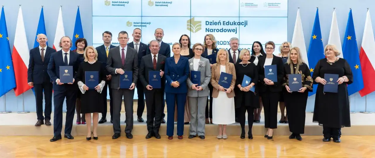 Grupa osób, w tym minister edukacji, odbiera dyplomy podczas uroczystości Dnia Edukacji Narodowej.