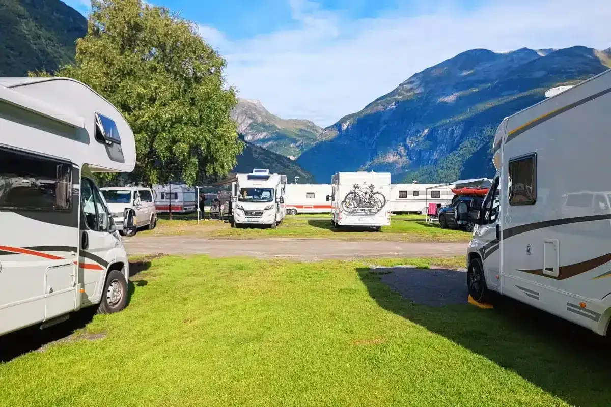 Autocaravanas low cost aparcadas en un camping con montañas al fondo. Unas vacaciones económicas y en plena naturaleza.