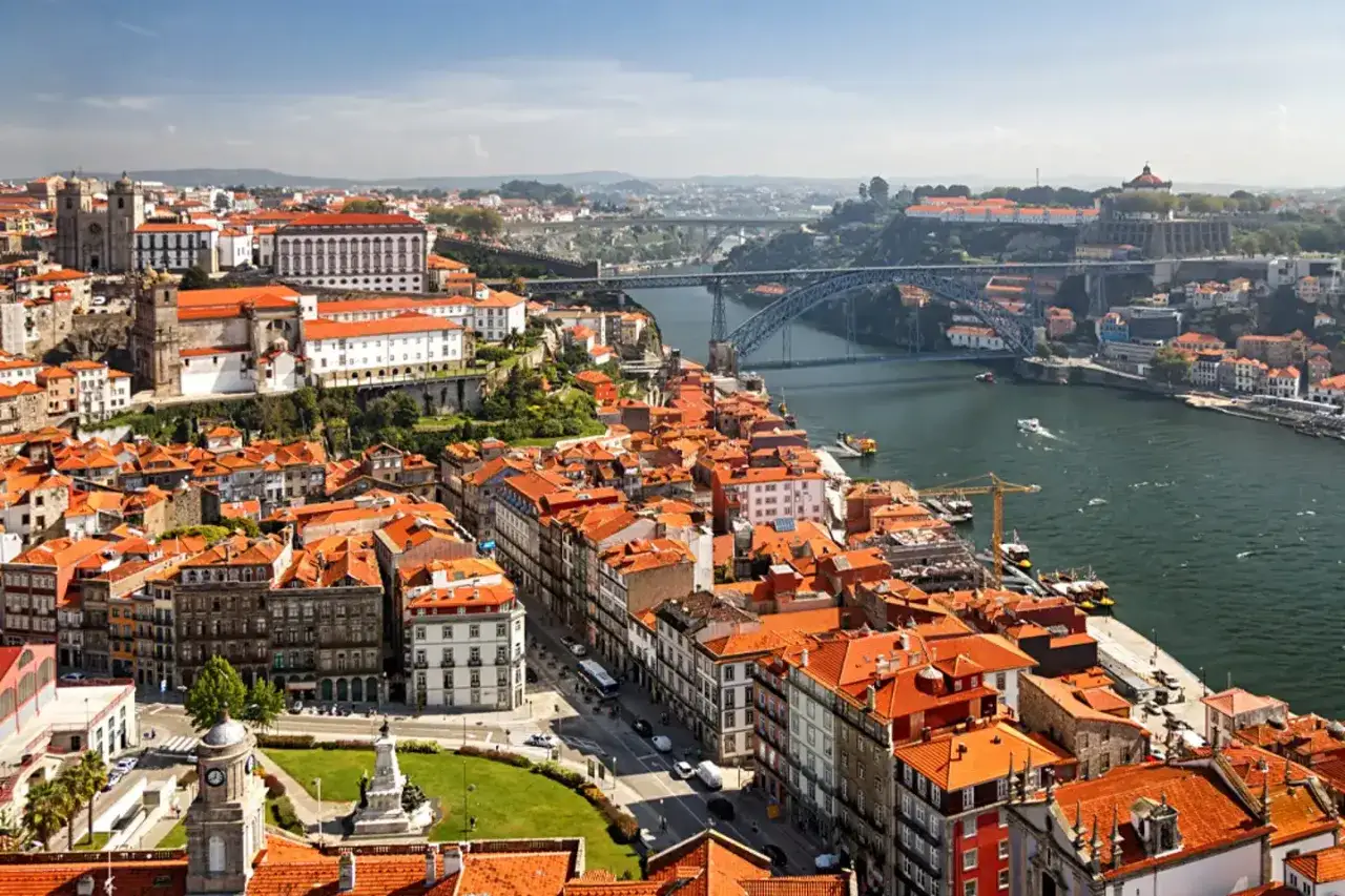 Widok na Porto z charakterystycznym mostem nad rzeką Duero. Czerwone dachy i zabytkowa architektura tworzą malowniczy krajobraz.