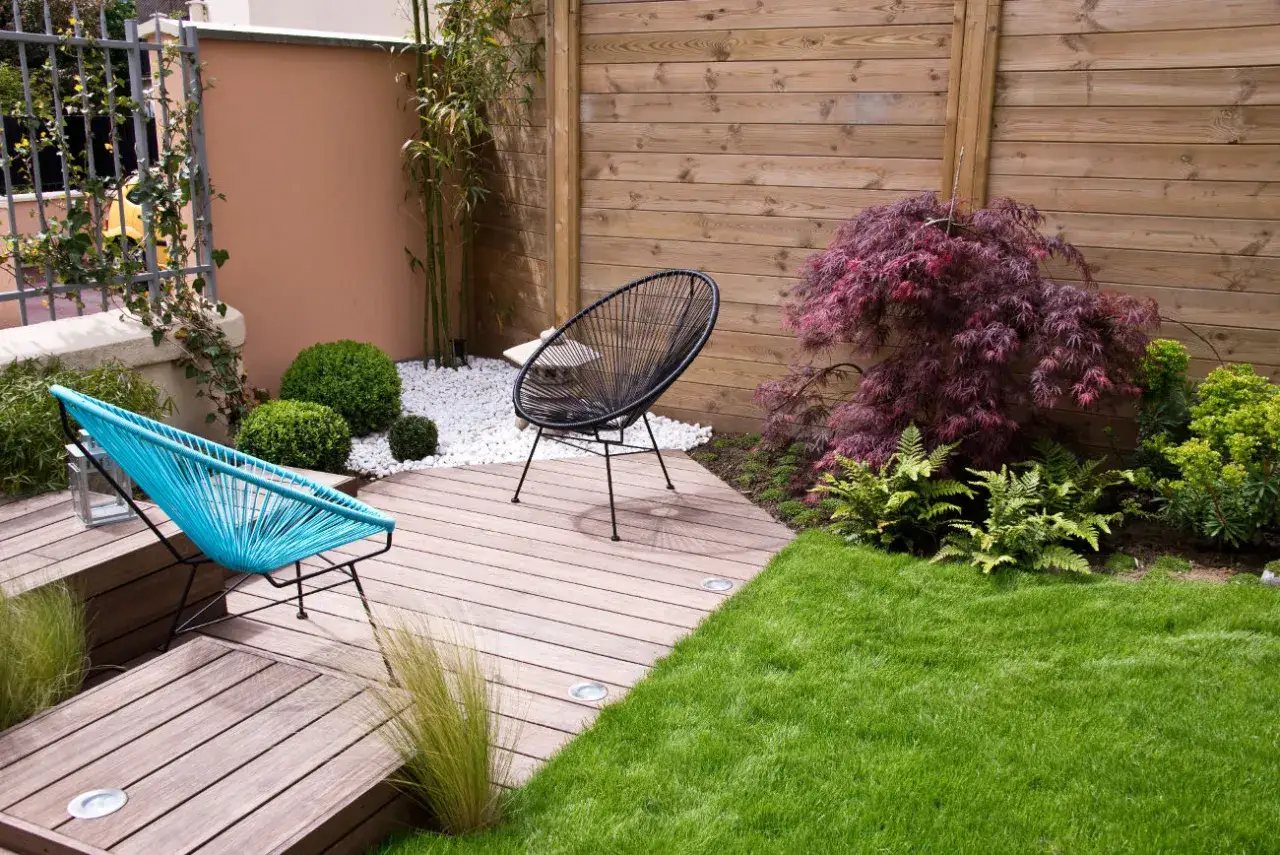 Un coin détente avec chaises colorées et un érable japonais. Un bel aménagement extérieur pour profiter du soleil.
