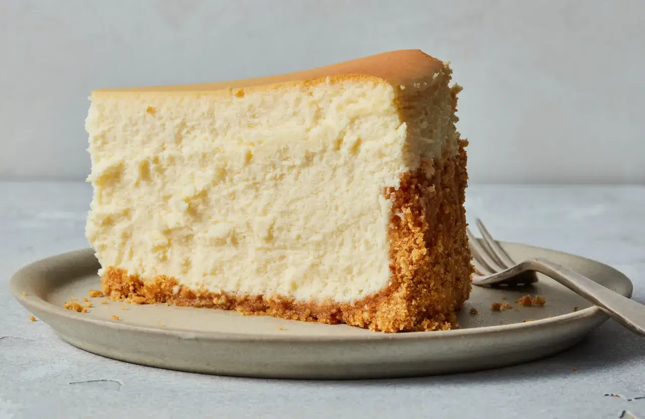 Ein Stück New York Cheesecake mit knusprigem Keksboden auf einem Teller, bereit zum Genießen.