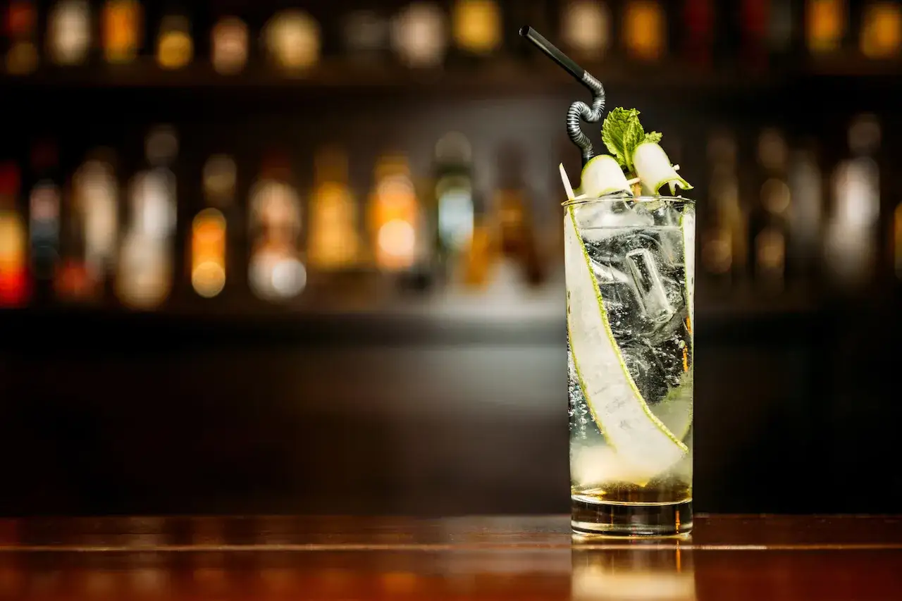 En svalkande Singapore Sling med gurka och mynta, redo att avnjutas vid en mörk bar.