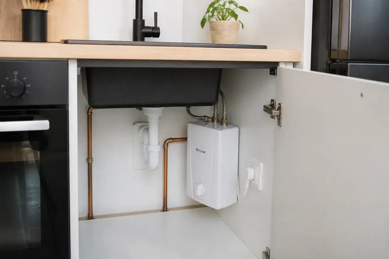 Sous un évier de cuisine, un chauffe-eau électrique instantané est visible. Ses inconvénients potentiels incluent une consommation électrique élevée.