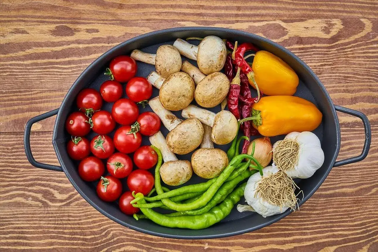 Warzywa na patelni: pomidorki, pieczarki, papryka, chili, czosnek i cebula. Idealne do dań paleo.