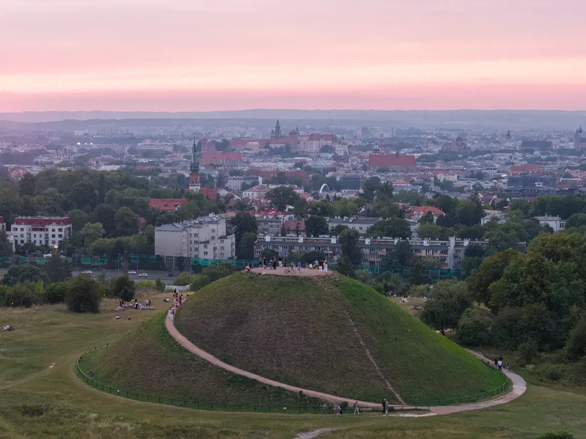 Zachód słońca nad Krakowem, z widokiem na Kopiec Krakusa i panoramę miasta.