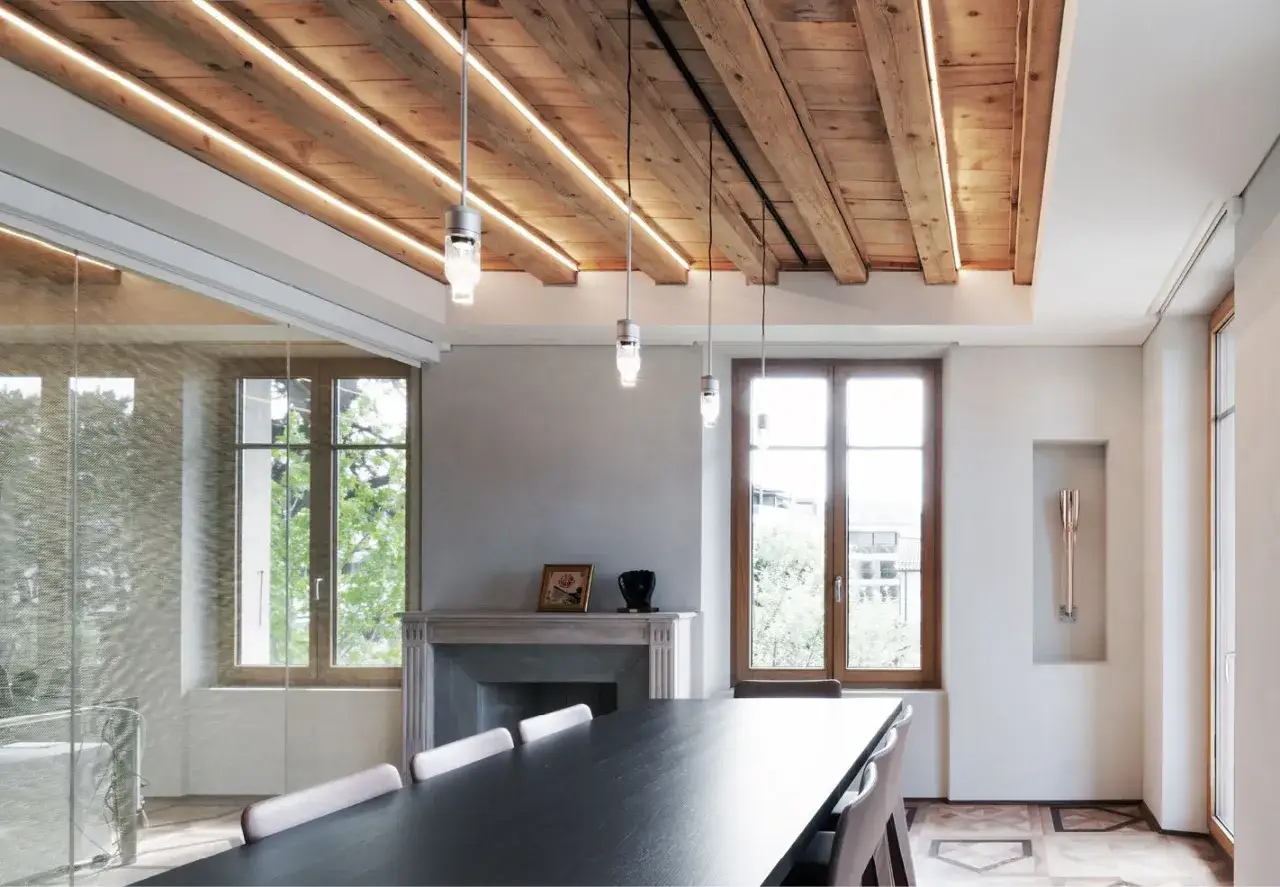 Soffitto con travi a vista moderne illuminate da LED, che creano un'atmosfera calda e accogliente.