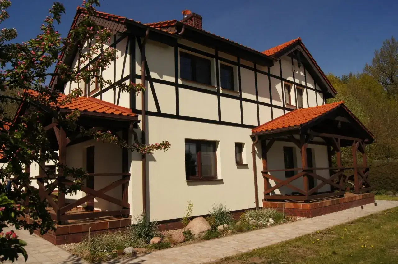 Urokliwe morska dębina domki letniskowe z charakterystyczną architekturą i drewnianymi werandami, otoczone zielenią.
