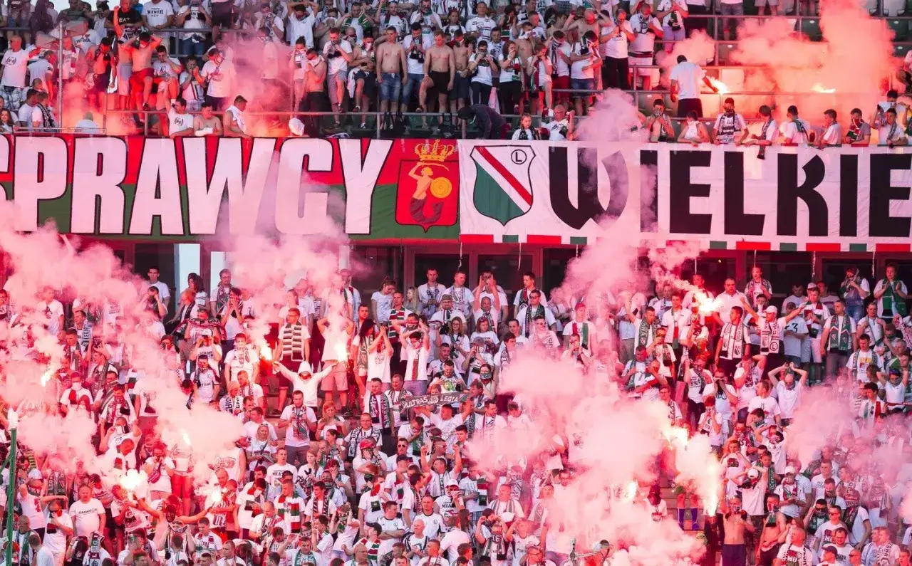 Tłum kibiców na stadionie, otoczony dymem z rac, świętuje sukcesy polskich klubów piłkarskich. Na banerze widnieje napis 