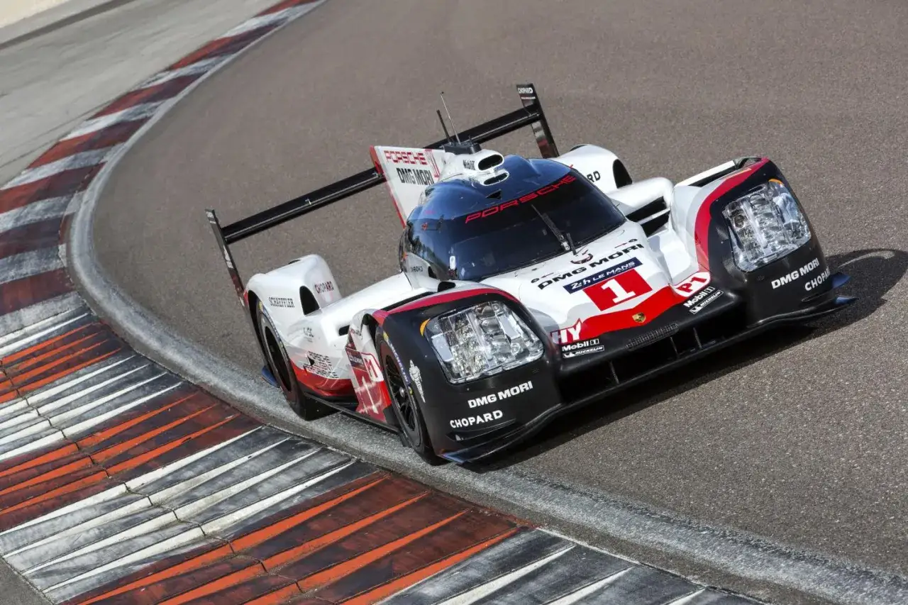 Porsche 919 na zakręcie toru wyścigowego, biało-czerwony bolid z numerem 1.