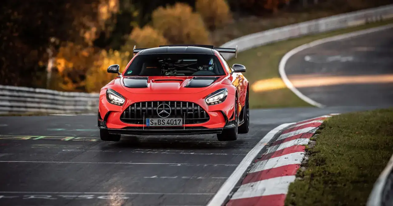 Czerwony Mercedes-AMG GT R na torze wyścigowym, z kierowcą w kasku za kierownicą.