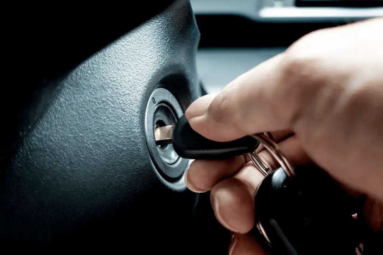 Main d'une personne insérant une clé dans le Neiman d'une voiture. Le prix du changement de Neiman est une préoccupation courante.