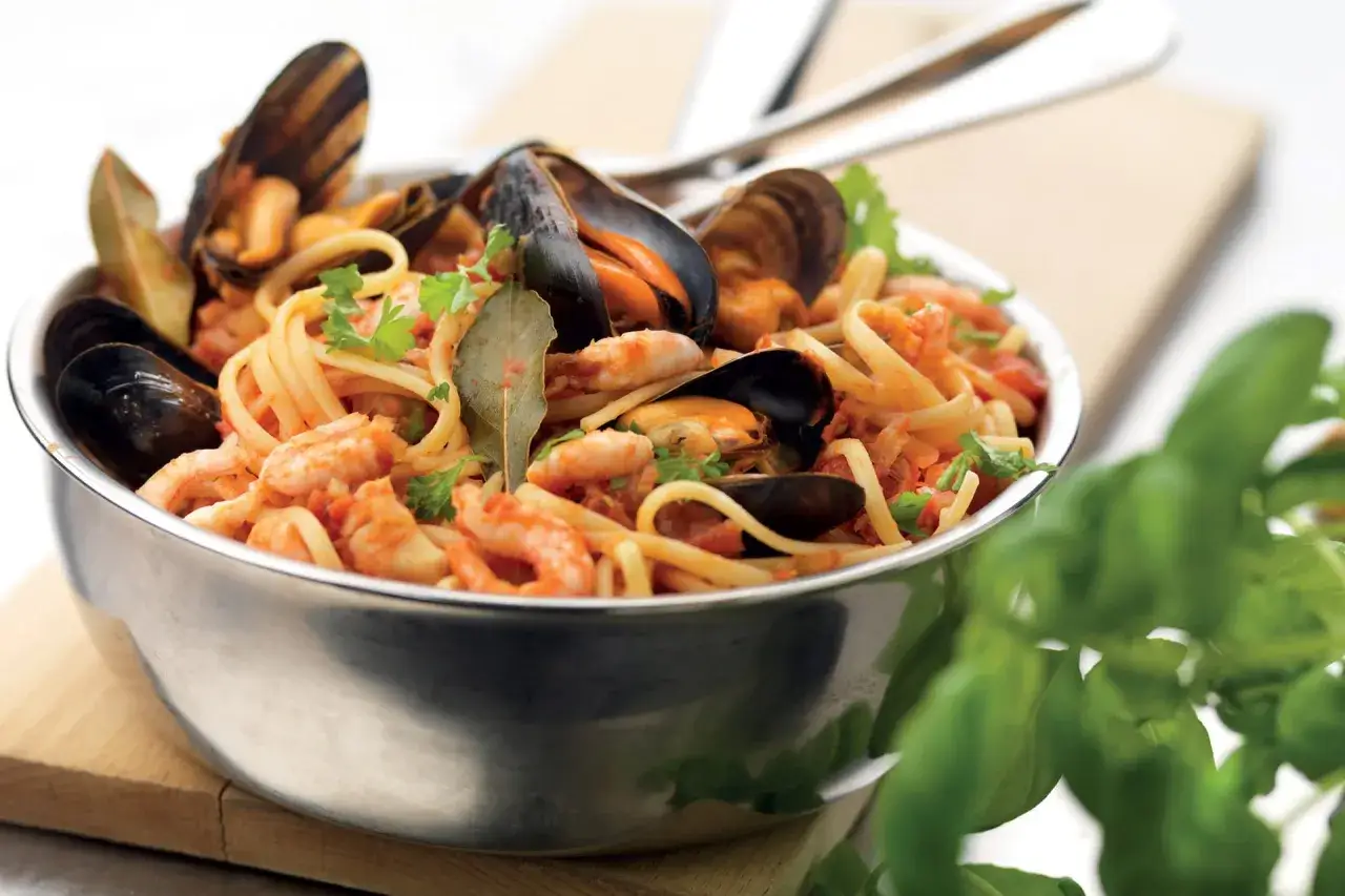 En skål med spaghetti allo scoglio, fylld med räkor, musslor och örter. En läcker italiensk pastarätt.