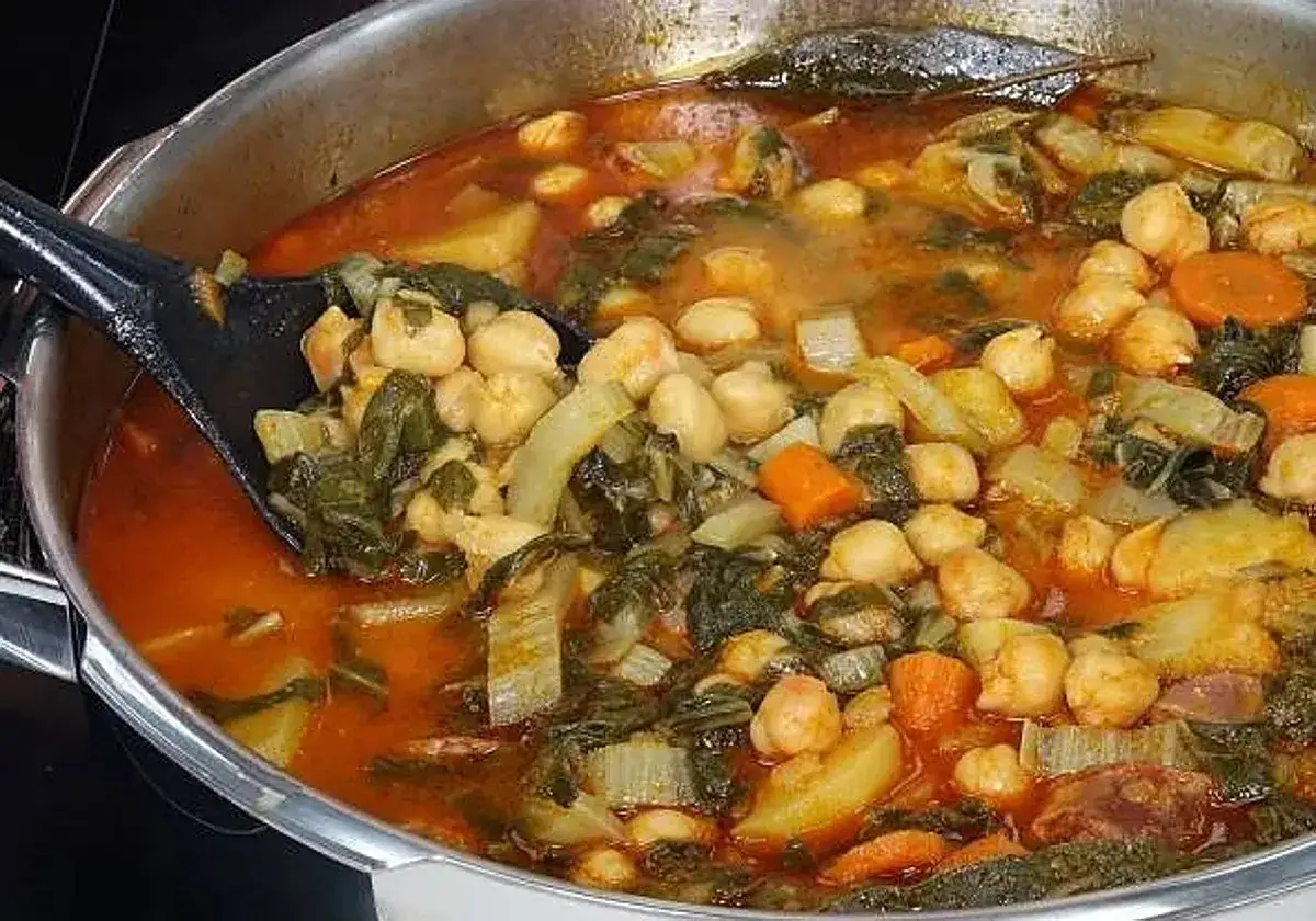 Un reconfortante guiso de garbanzos con acelgas, patatas y zanahorias en una olla grande.
