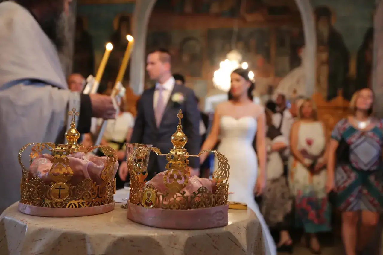 Złote korony i płonące świece zapowiadają uroczysty ślub prawosławny. W tle dostojnie prezentuje się para młoda.