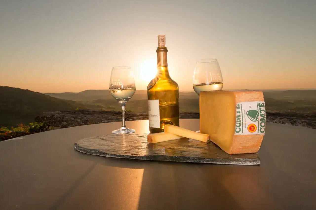 Dégustation de vin blanc du Jura et de Comté au coucher du soleil. Une invitation à la gastronomie Jura.