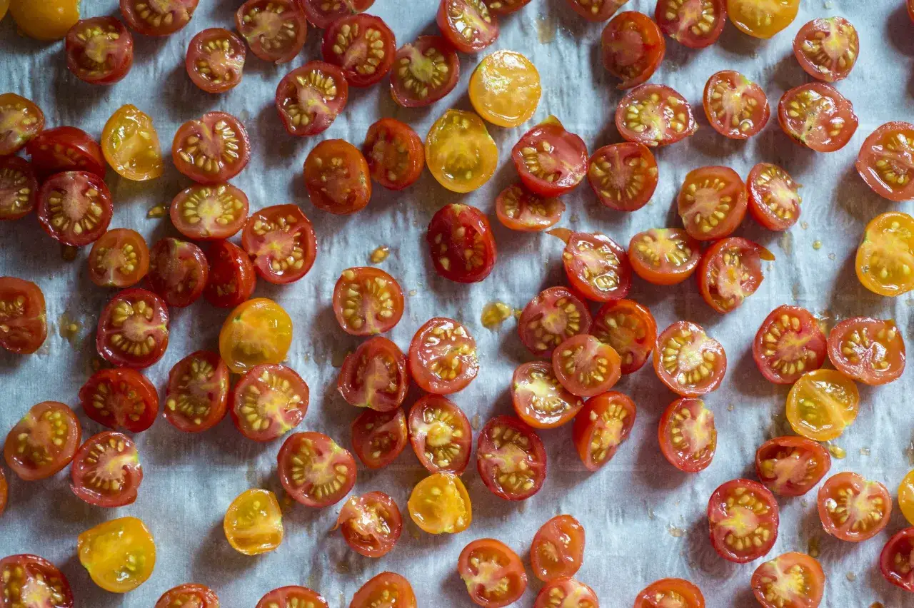 Tomates cerises coupées en deux, prêtes pour une recette de tomates séchées. Des couleurs vives pour un plat savoureux.